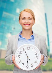 Image showing smiling businesswoman with wall clock