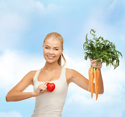 Image showing smiling woman holding heart symbol and carrots