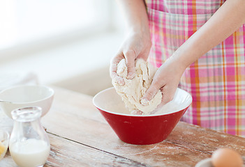 Image showing close up of female hands kneading dough at home