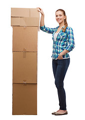 Image showing young woman standing next to tower of boxes