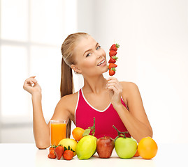 Image showing smiling woman with organic food eating strawberry