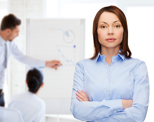 Image showing smiling businesswoman with crossed arms at office