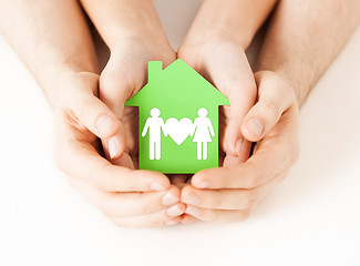 Image showing hands holding green house with family