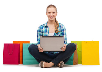 Image showing smiling girl with laptop comuter and shopping bags