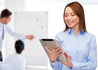 Image showing smiling woman looking at tablet pc at office