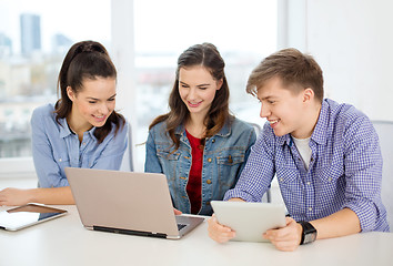 Image showing three smiling students with laptop and tablet pc