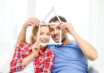 Image showing smiling couple with house from measuring tape