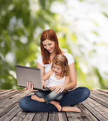 Image showing happy mother with adorable little girl and laptop