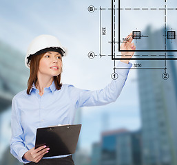 Image showing smiling businesswoman in helmet with clipboard