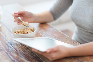 Image showing woman eating porridge and using tablet pc