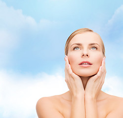 Image showing beautiful woman touching her face and looking up