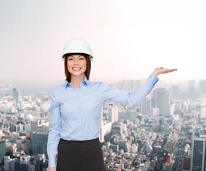 Image showing businesswoman in helmet holding something on palm