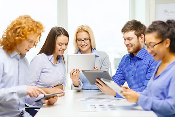 Image showing smiling team with table pc and papers working