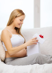 Image showing smiling pregnant woman opening gift box