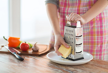 Image showing close up of female hands grating cheese