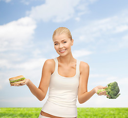 Image showing smiling woman with broccoli and hamburger