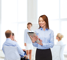 Image showing smiling woman looking at tablet pc at office