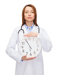 Image showing calm female doctor with wall clock