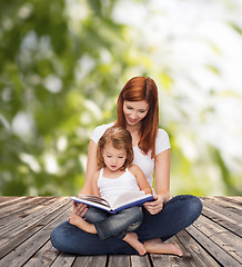 Image showing happy mother with adorable little girl and book
