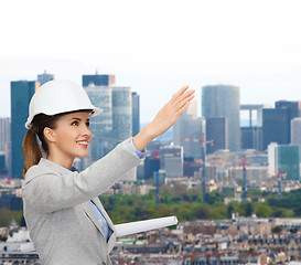 Image showing smiling architect in white helmet with blueprints