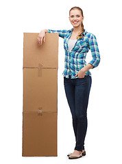 Image showing young woman standing next to tower of boxes