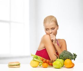 Image showing doubting woman with fruits and hamburger