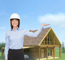 Image showing businesswoman in helmet holding something on palm