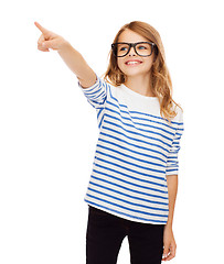 Image showing cute little girl in eyeglasses pointing in the air