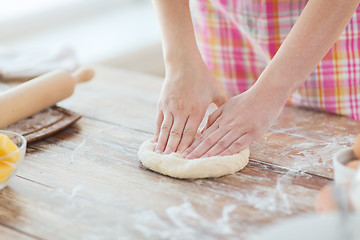 Image showing close up of female hands kneading dough at home