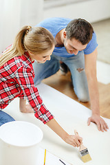 Image showing smiling couple smearing wallpaper with glue