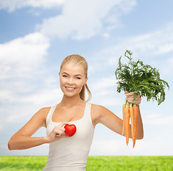 Image showing smiling woman holding heart symbol and carrots