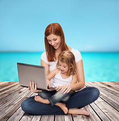Image showing happy mother with adorable little girl and laptop