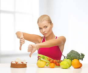 Image showing woman with fruits showing thumbs down to cake