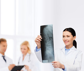 Image showing smiling female doctor looking at x-ray