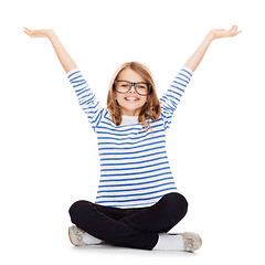 Image showing smiling girl in eyeglasses sitting on floor