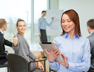 Image showing smiling woman looking at tablet pc at office