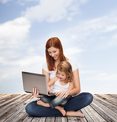 Image showing happy mother with adorable little girl and laptop