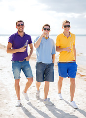 Image showing male friends on the beach with bottles of drink