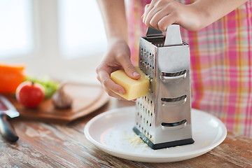 Image showing close up of female hands grating cheese