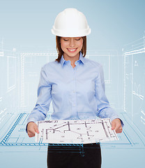 Image showing businesswoman in helmet looking at blueprint