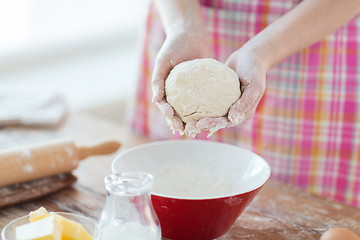 Image showing close up of female hands kneading dough at home