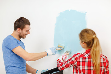 Image showing smiling couple painting wall at home