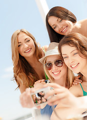 Image showing smiling girls taking photo in cafe on the beach