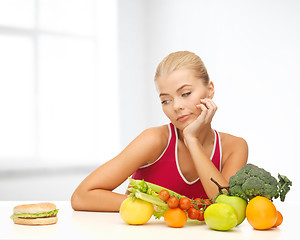 Image showing doubting woman with fruits and hamburger