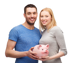 Image showing smiling couple holding big piggy bank