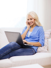 Image showing smiling woman with smartphone and laptop at home