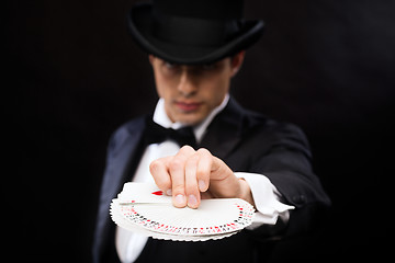 Image showing magician in hat showing trick with playing cards