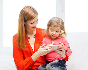 Image showing happy mother and daughter with smartphone at home