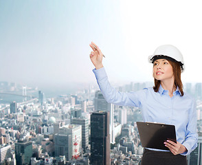 Image showing smiling businesswoman in helmet with clipboard