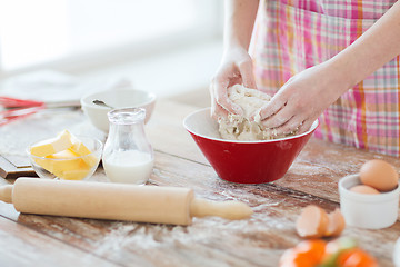 Image showing close up of female hands kneading dough at home